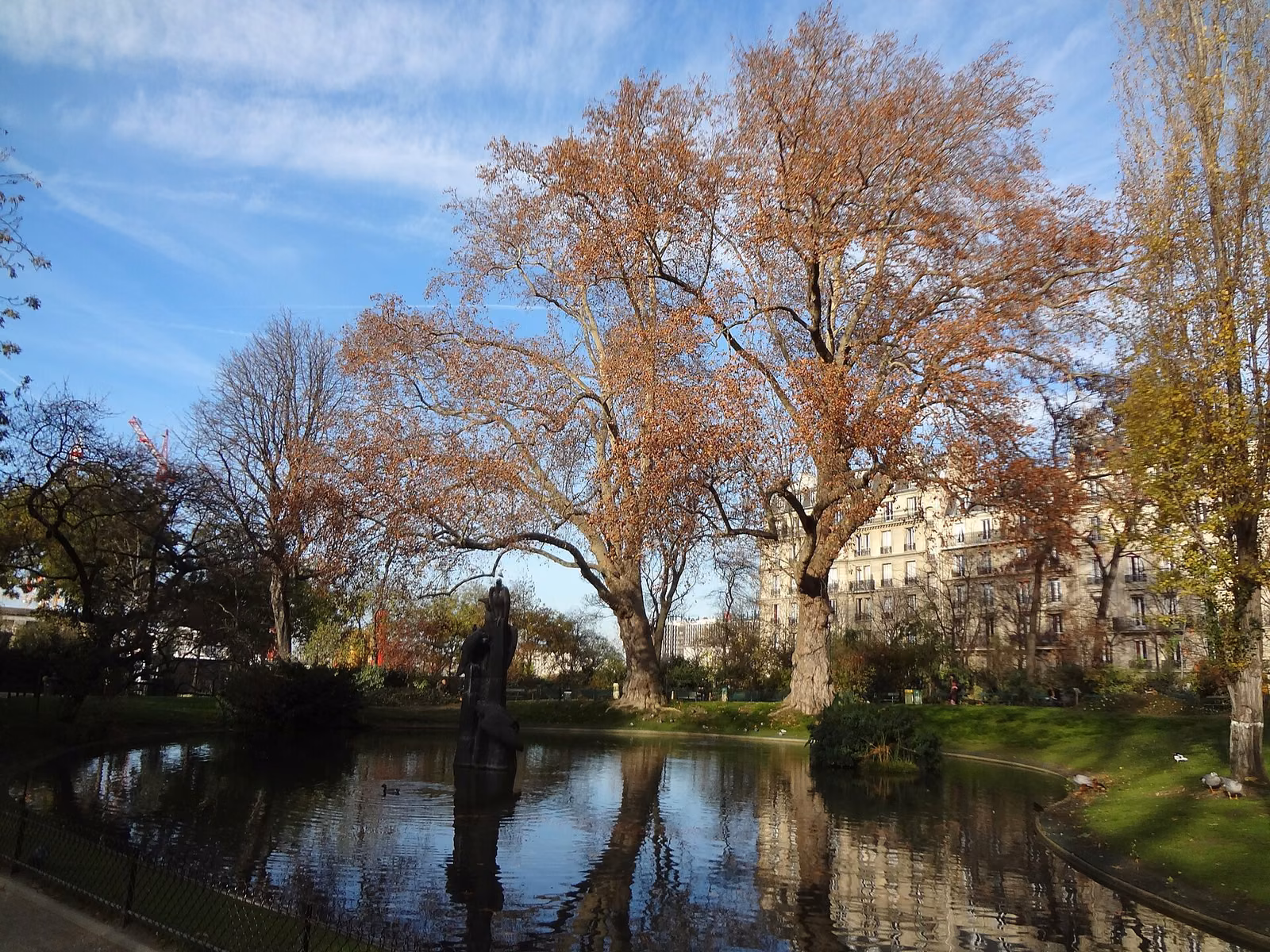 Bassin du square des Batignolles avec la sculpture Les Vautours, entouré d’arbres, Paris 17e.